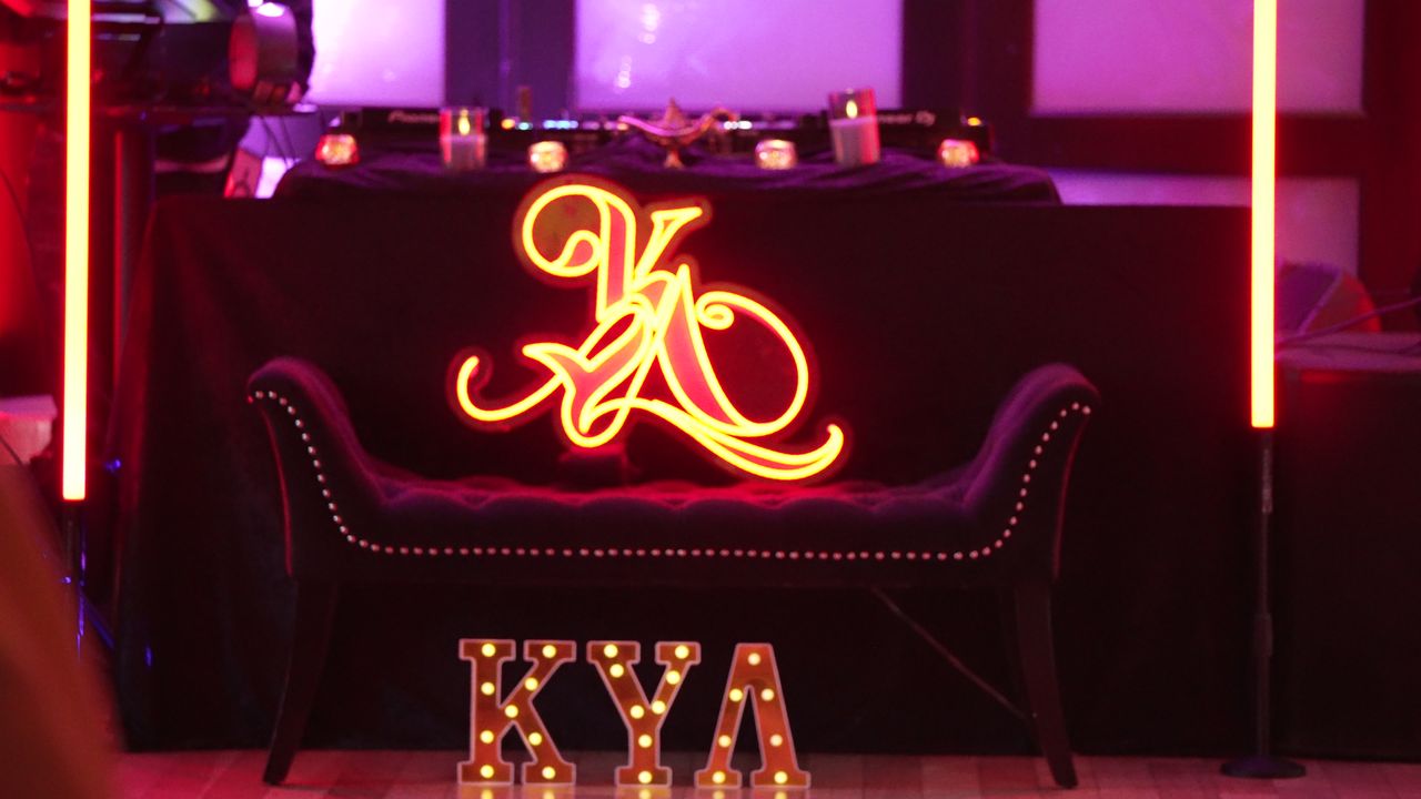 The KYA KLUB DJ booth with its neon logo, velvet bench and marquee letters