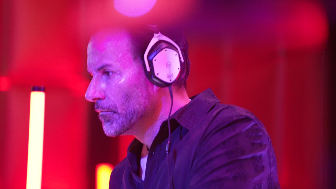 A KYA KLUB resident DJ in white headphones mixing under red and purple light