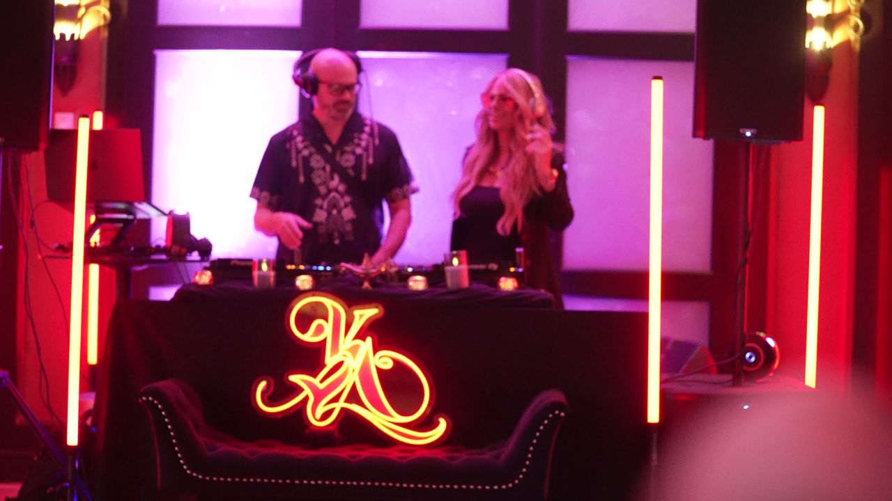A DJ and Maria Matarelli at the KYA KLUB booth under purple light